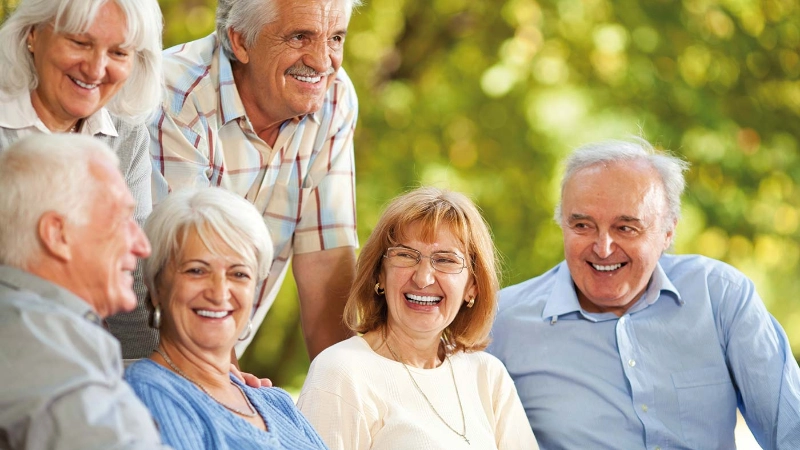 Seniorinnen und Senioren lachend beisammen im Freien