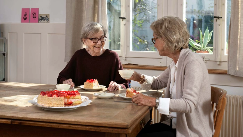 Frau besucht Seniorin zuhause.