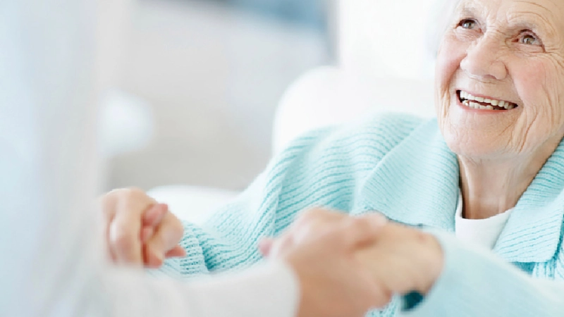 Frau reicht Seniorin die Hände zur Hilfe.