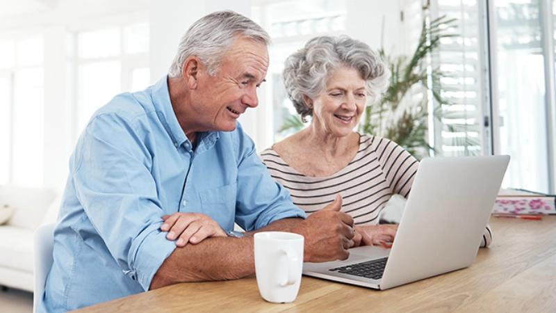 älteres Paar am Tisch schauen in Laptop