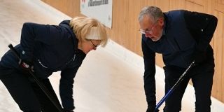 Eine Frau und ein Mann beim Curling spielen.