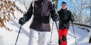 Eine ältere Frau und ein älterer Herr beim Schneeschuhlaufen.