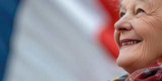 Seniorin lächelt, hinter ihr ist die französische Flagge.