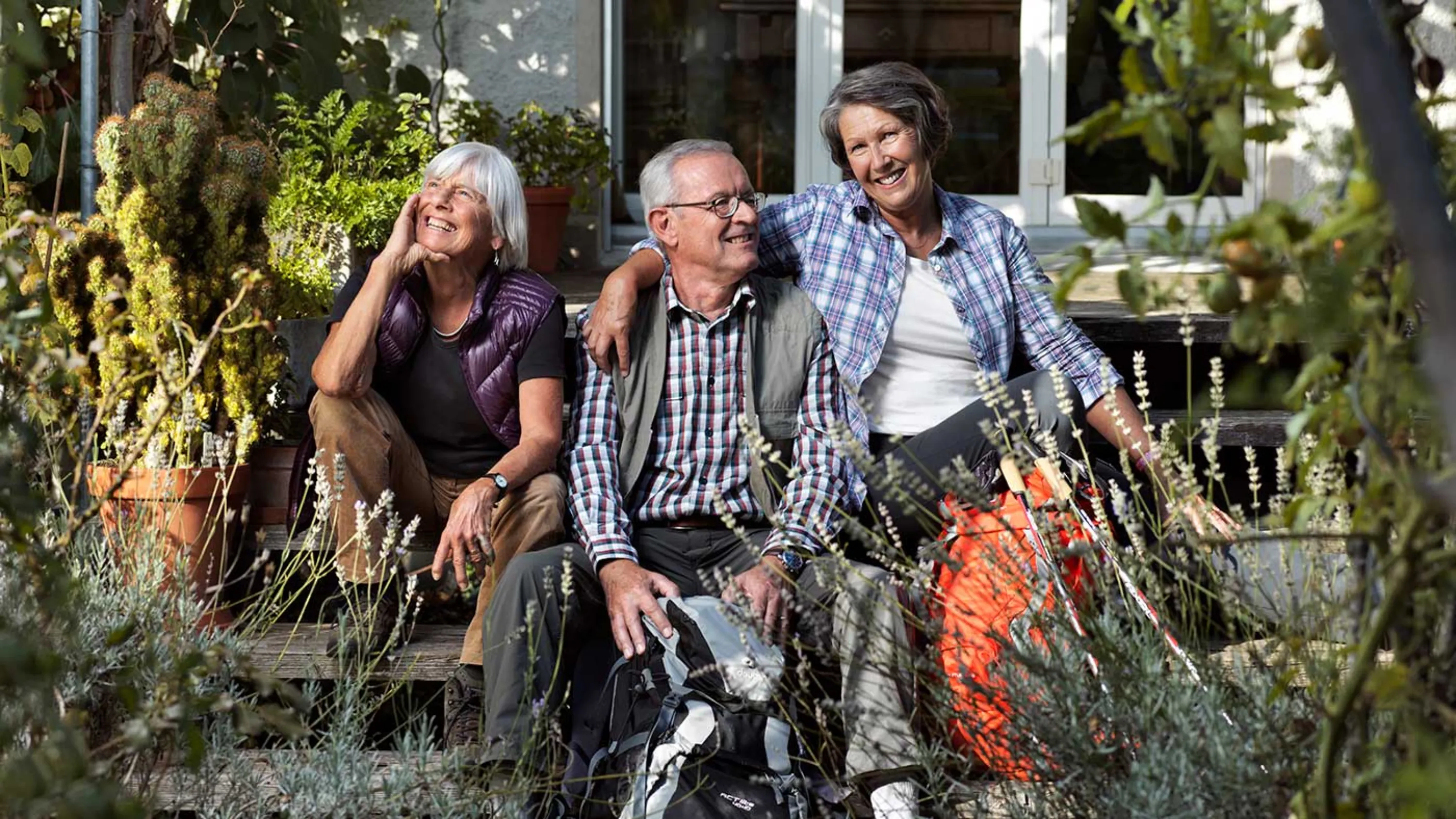 Drei Seniorinnen und Senioren machen beim Wandern eine Pause.