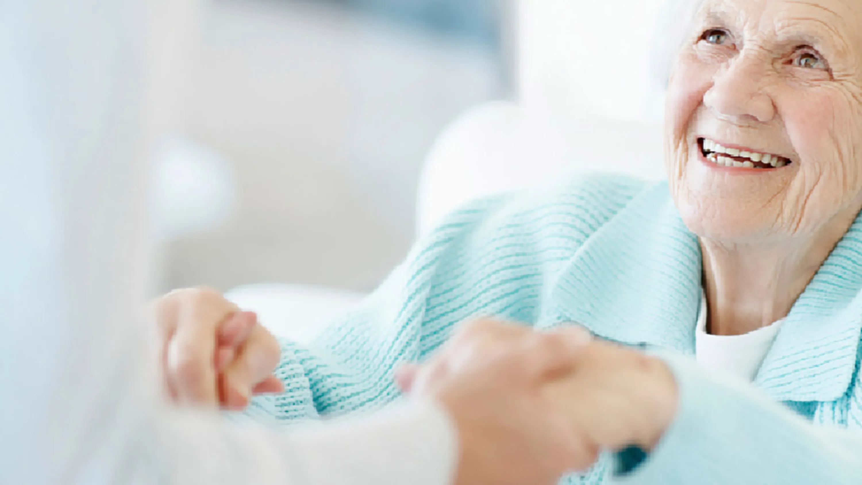 Frau reicht Seniorin die Hände zur Hilfe.