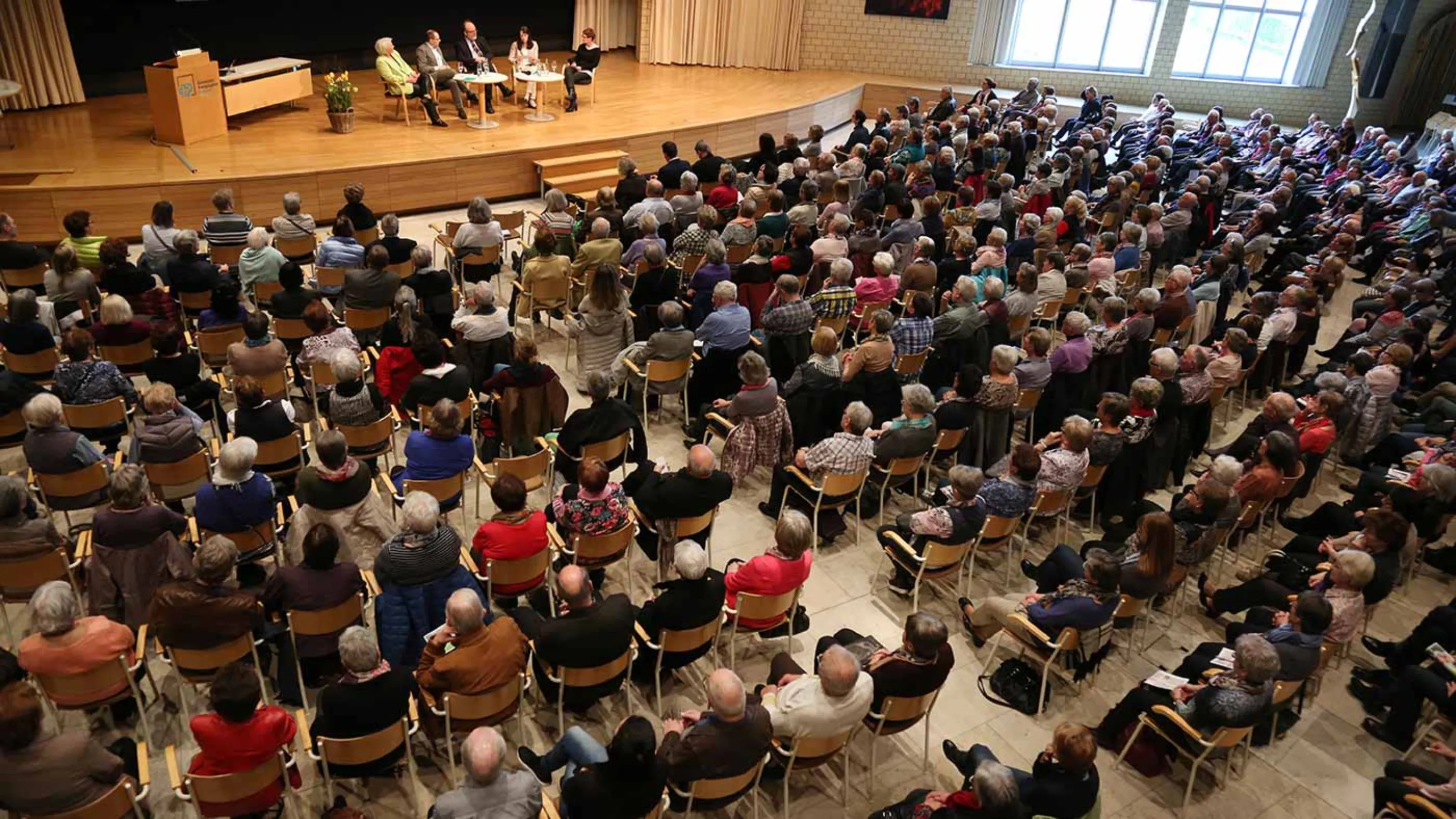 Blick von oben auf einen Saal mit voll gefüllten Besucherreihen.