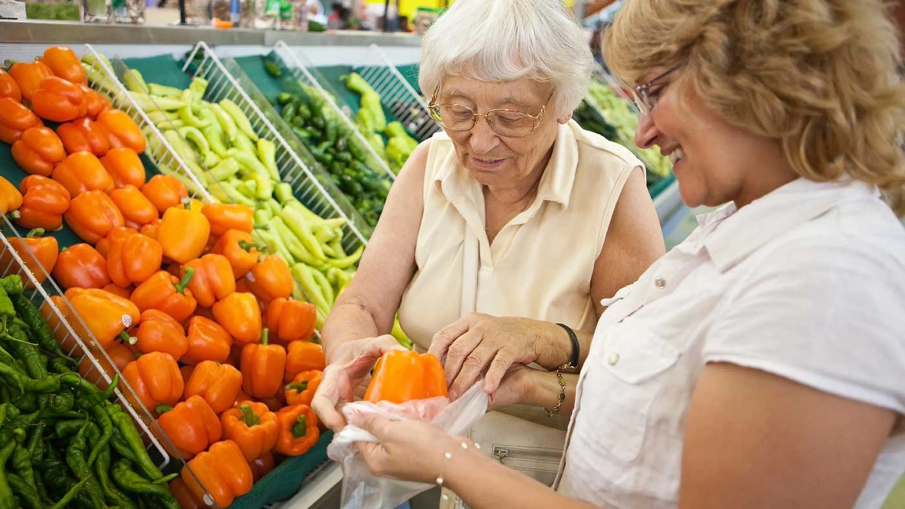 Eine Frau hilft einer Seniorin beim Einkaufen.