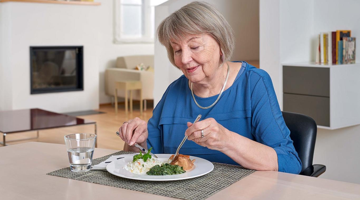 Une femme est assise à une table et mange.