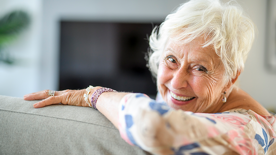 ältere Frau auf Sofa lachend in Kamera