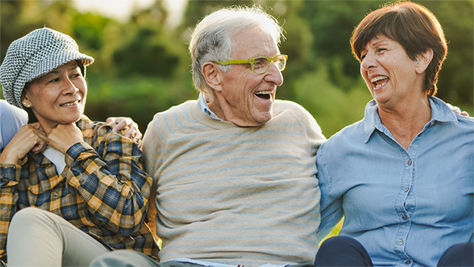 lachende ältere Menschen draussen auf sitzend