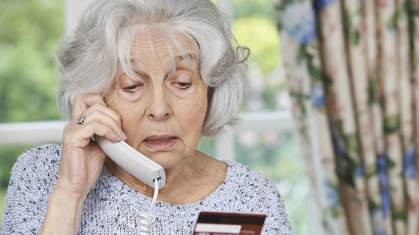 ältere Frau am Telefon mit Kreditkarte in der Hand