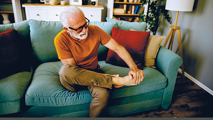 Mann auf Sofa massiert seine Füsse