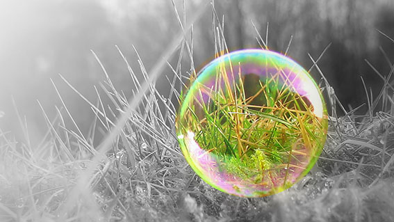 Die farbige Seifenblase auf dem grauen Gras symbolisiert Hoffnung.