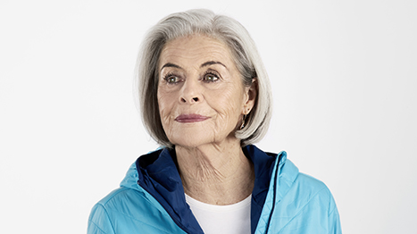 Frau lächelnd in Sportkleidung mit Velohelm unter dem Arm  